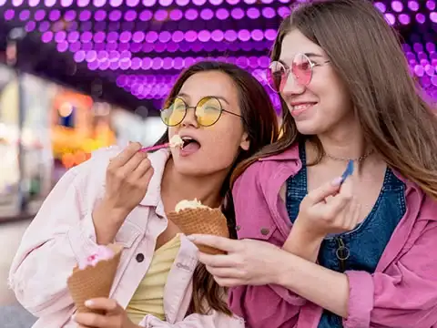 Home 63 Two friends smiling and sharing a Keds Ice Cream cone